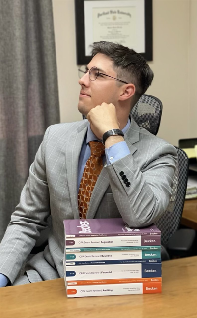 Spencer looking off with elbow on stack of CPA books so he could take the linkedin style photo