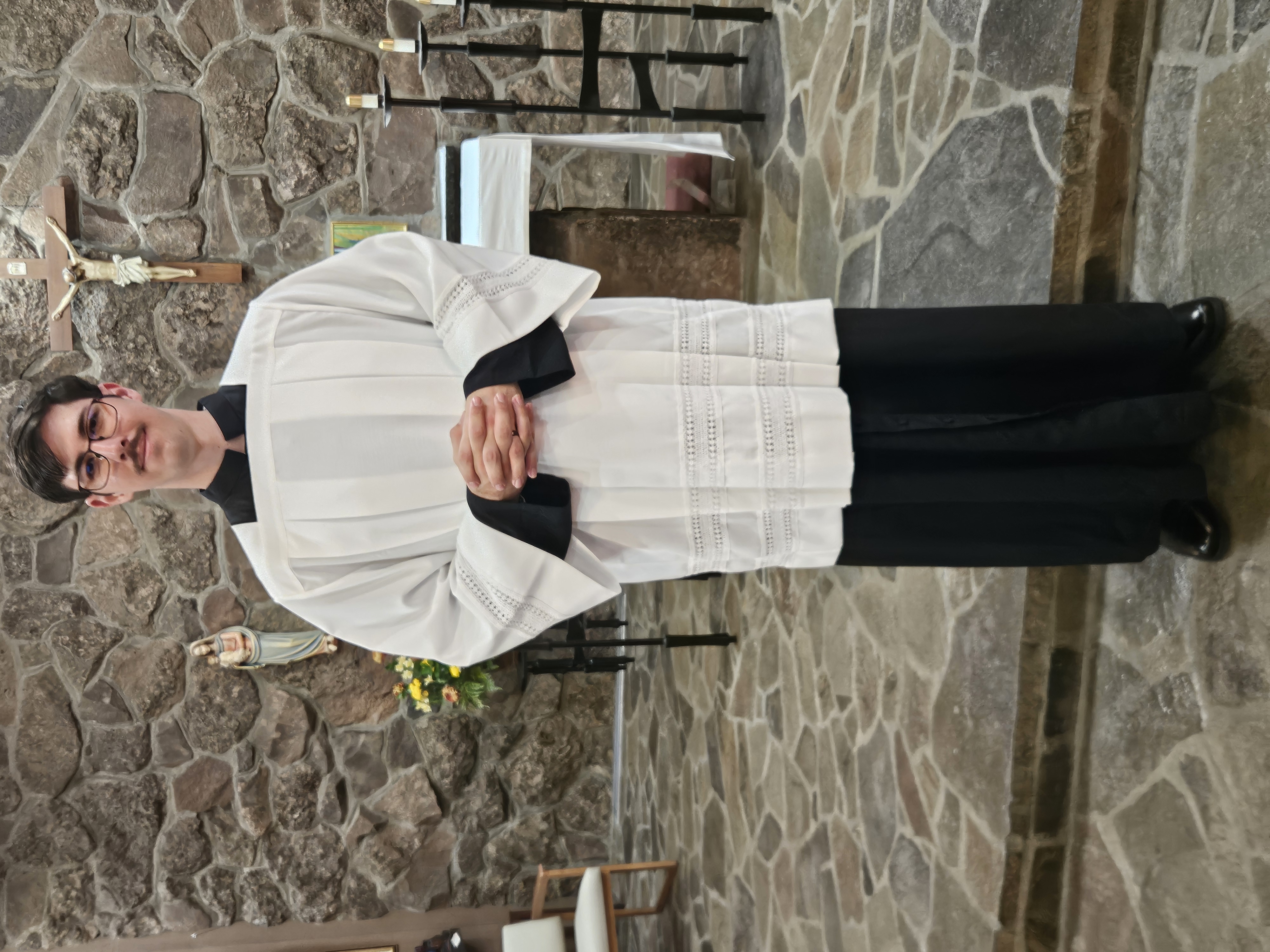 person standing inside of church wearing black cassock and white surplice